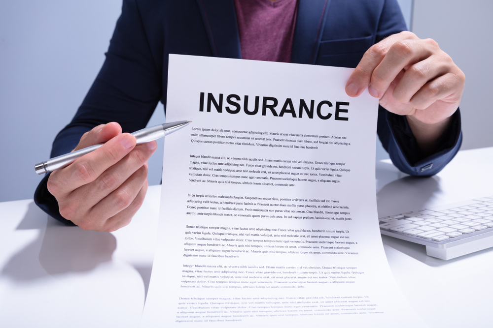man holding up a paper with the word insurance on it