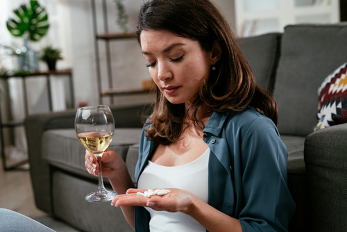 woman taking pills with wine