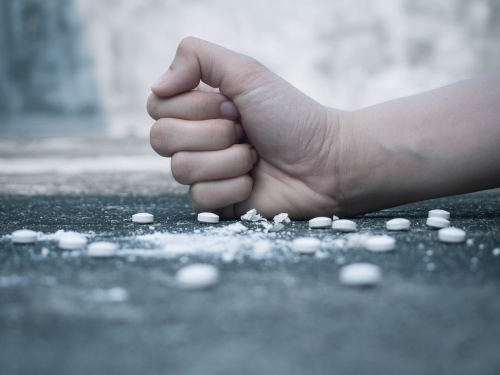 hand crushing pills on the ground