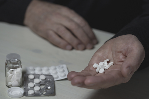 person holding a handful of snortable pills with packages sitting on table