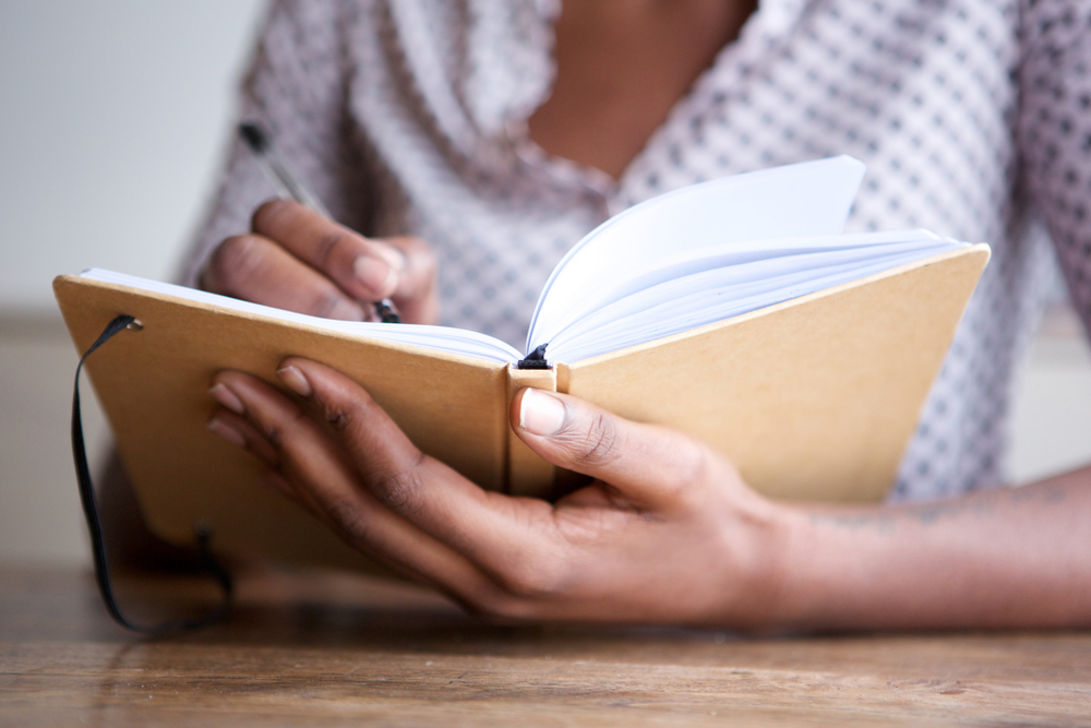 person writing in a sobriety journal