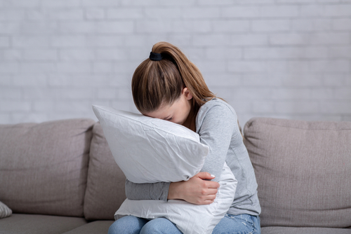 woman hugging pillow while being upset