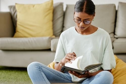 woman looking through the pages of her sobriety journal while sitting on the floor