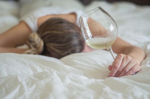 woman laying on bed with glass of wine in her hand due to alcohol blackouts personality changes