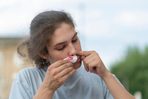 young person holding bloody nose