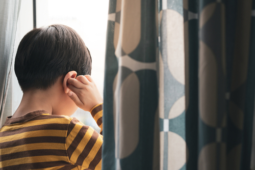 young boy plugging his ears to block out sounds of domestic abuse