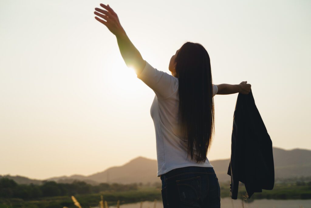 medium happy business woman spreading arms and watching the mountain silhouette business success concept freedom emotions